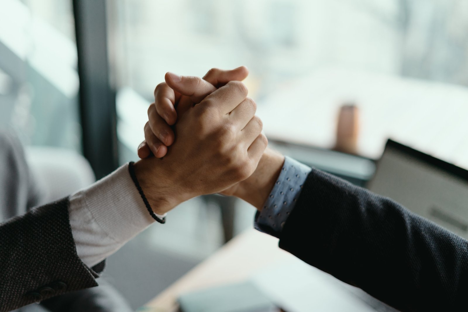 Close up two businessmen shaking hands. Positive management team celebrating victory, successful stock deal, sales growth, won good contract, business achievement and teamwork concept